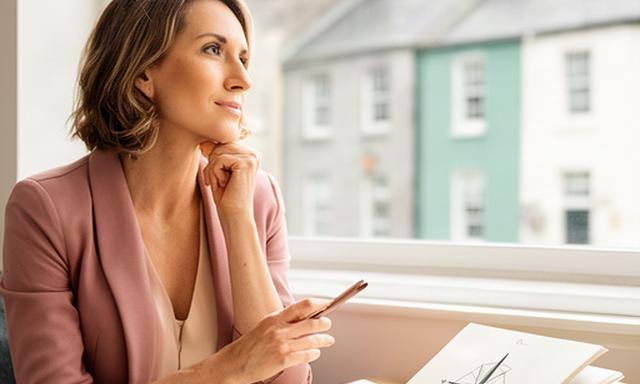 Professional woman reviewing career notes beside a bright Dublin window with a compass notebook